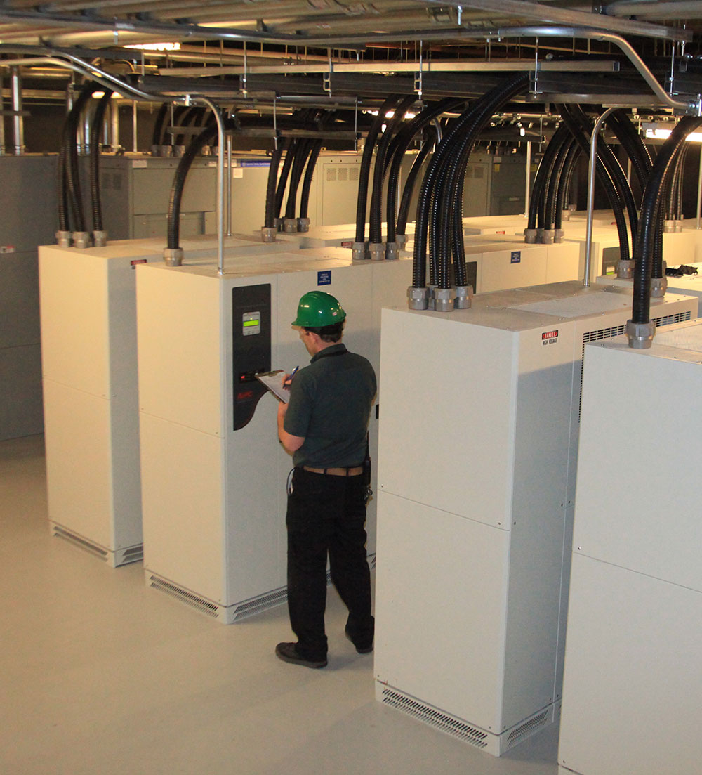 Service technician writing down equipment readings during in a data centre.