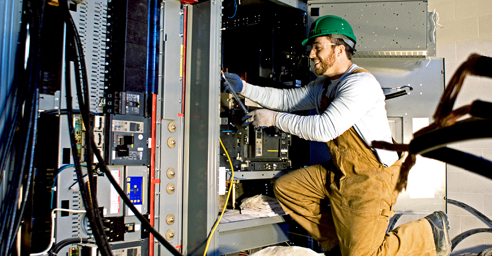 Construction worker wiring a main distribution board on a new build site.